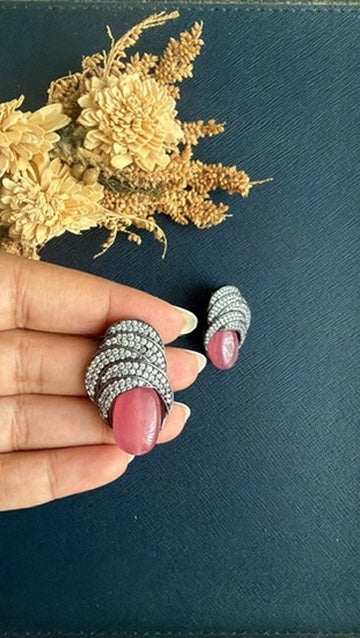 Pink doublet stone stud with wave bands of white American Diamond pavé on a dark Victorian finish, held in hand