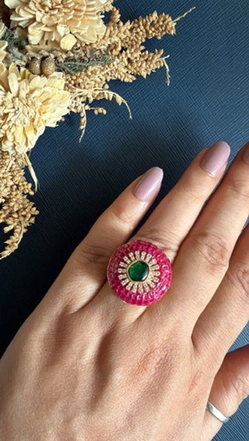 Ruby red adjustable ring in matt gold worn on hand, green centre stone with magic setting
