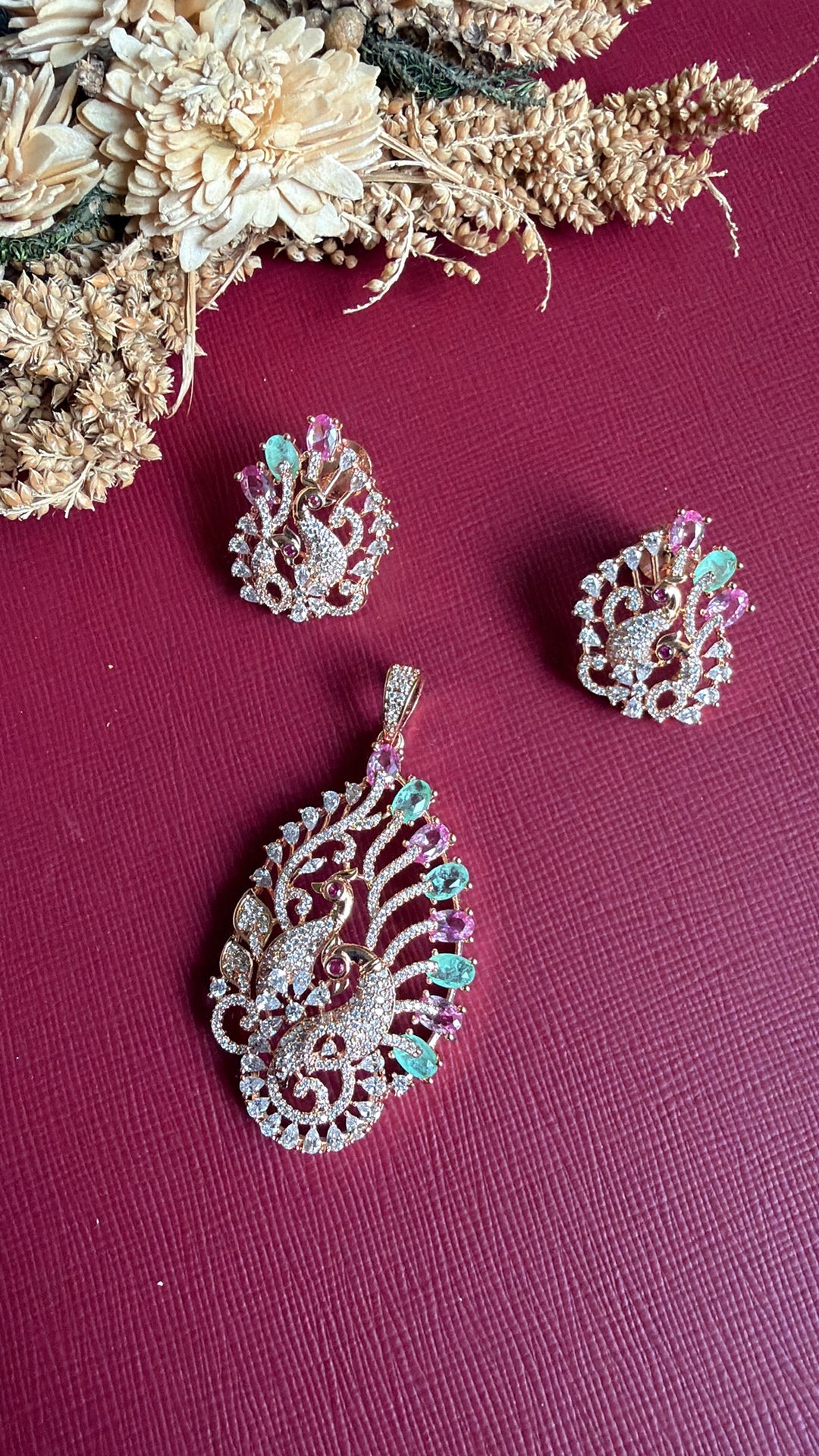 Emaan peacock stud earring held in hand with matching rose gold pendant