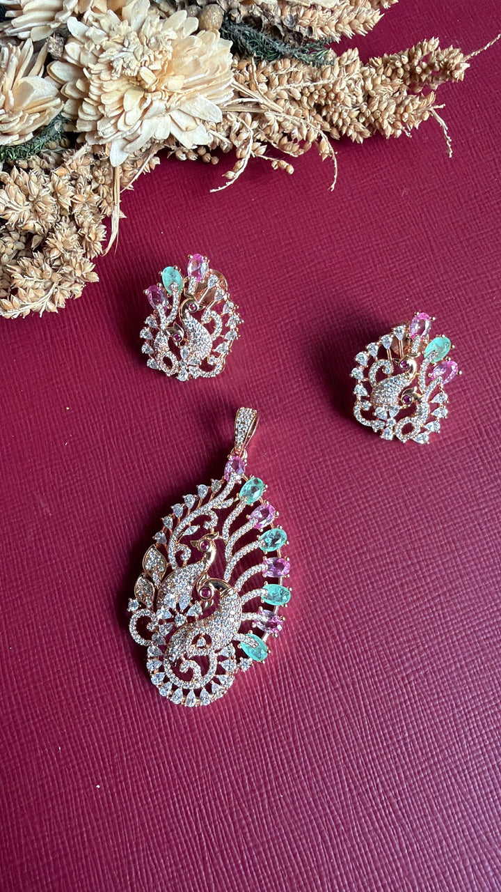 Emaan peacock stud earring held in hand with matching rose gold pendant