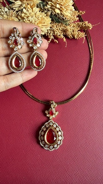 Clara ruby-red drop earrings held in hand to show their size, beside the Victorian hasli pendant