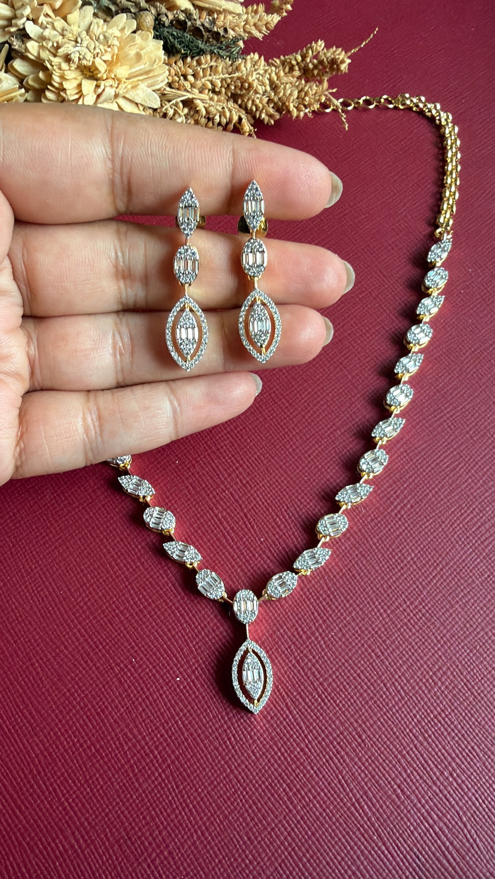 Gianna three-tier American Diamond drop earrings held in hand with matching necklace
