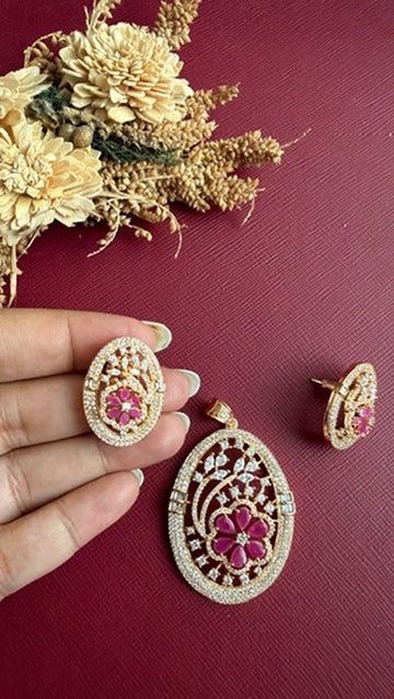 Mishka stud earring held in hand to show its size, beside the oval pendant