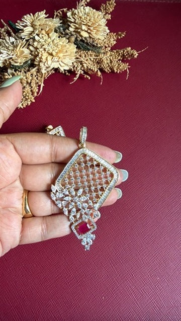 Clara geometric pendant held in hand to show its size: baguette frame, lattice centre and ruby-pink drop
