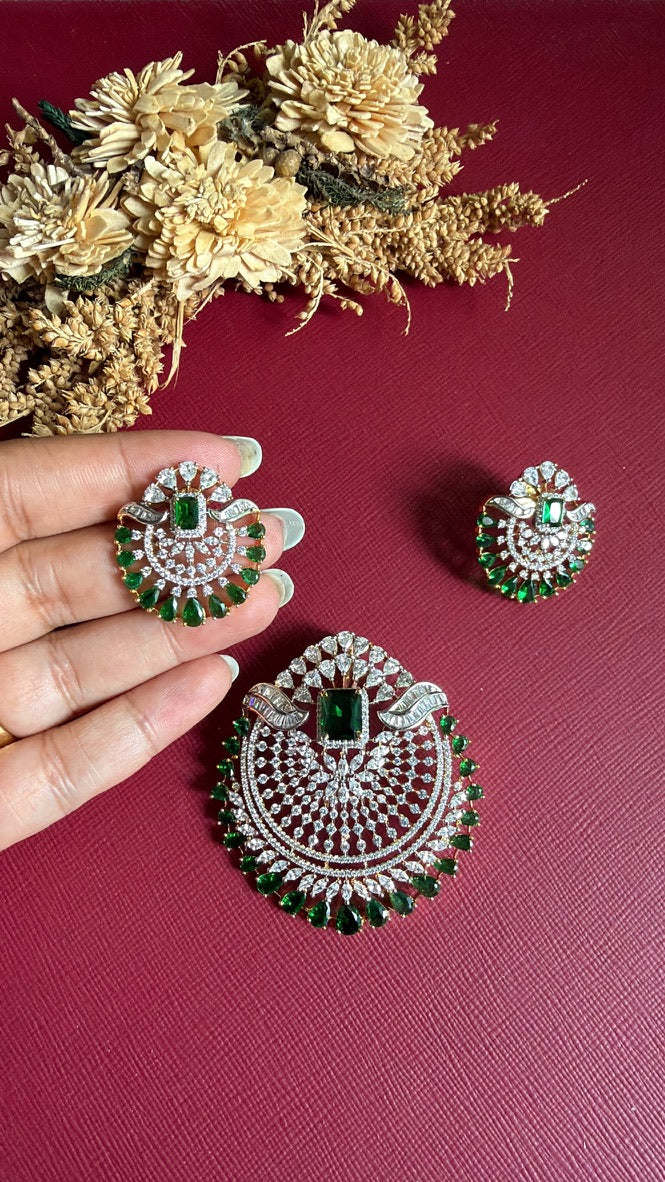Rushika Green earring held in hand to show its size, with green centre stone and green pear-drop border