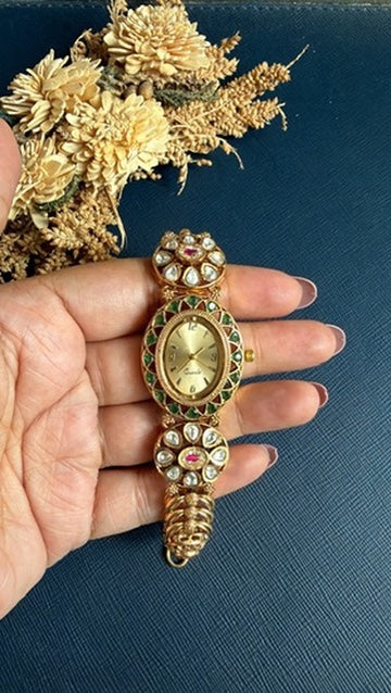 Archana ethnic watch bracelet held in hand – white Kundan stones with ruby-pink centres in matt gold polish