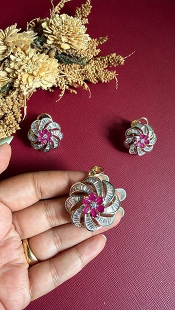 Mansi ruby-pink and white American Diamond swirl pendant held in hand, with earrings above