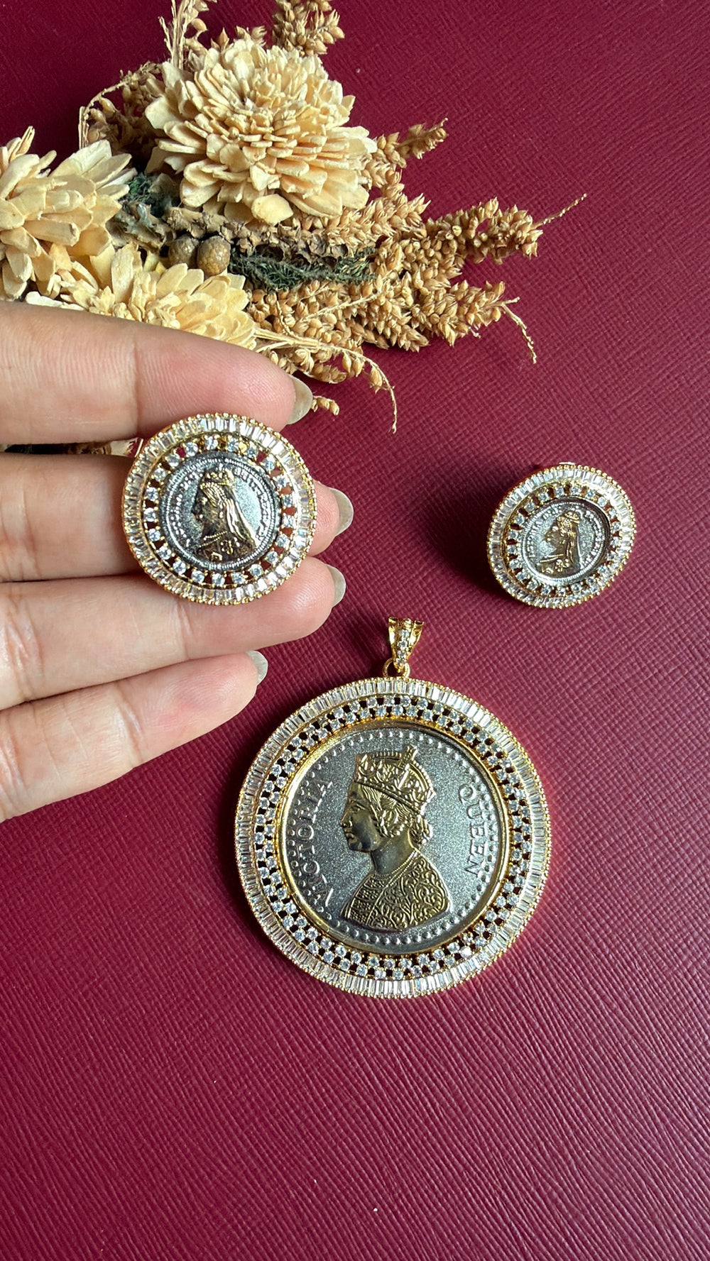 Ginni coin stud held in hand with matching dual-tone coin pendant