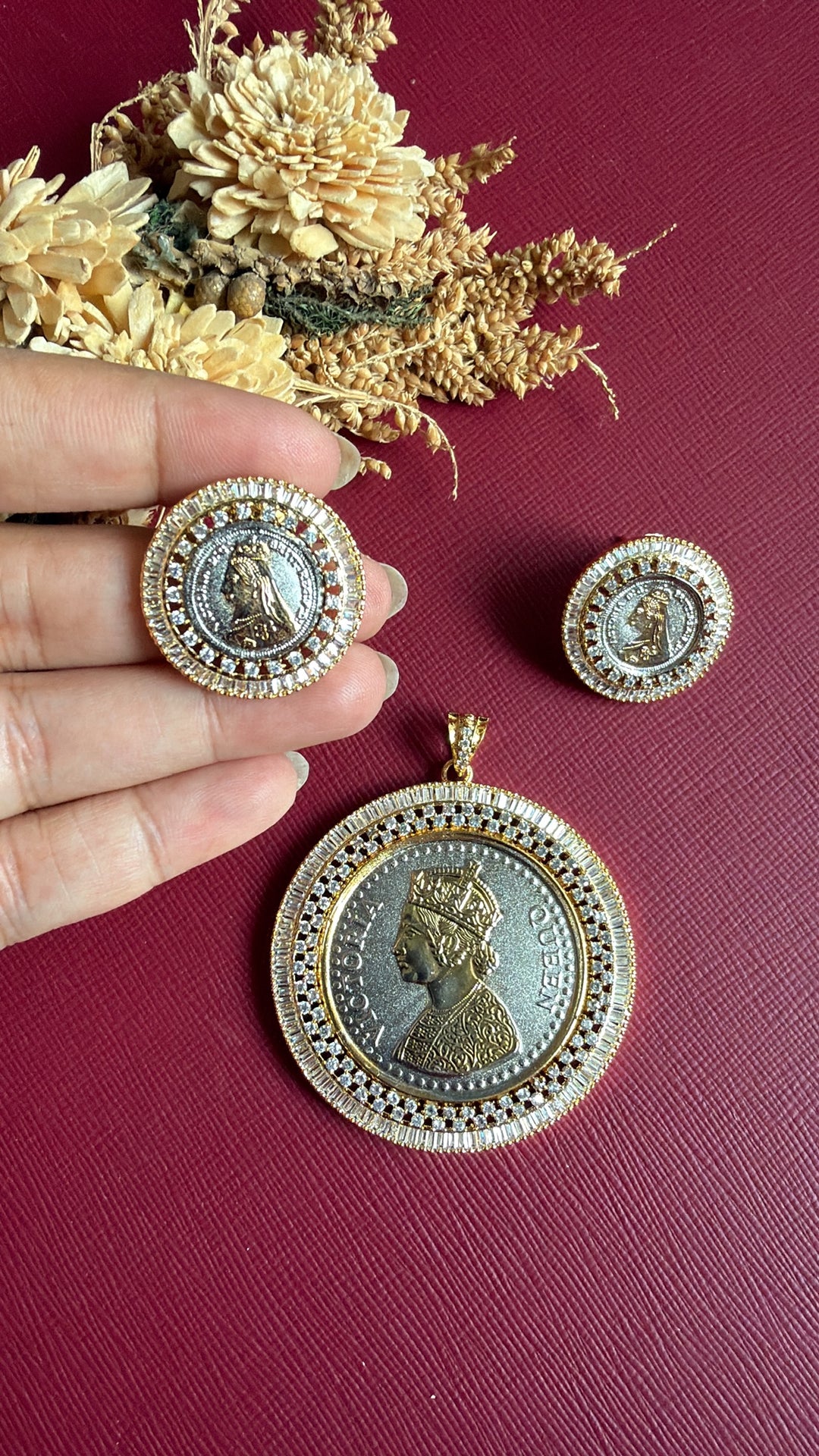 Ginni coin stud held in hand with matching dual-tone coin pendant