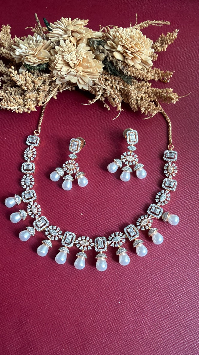 Tanirika white American Diamond necklace with emerald-cut stones, sunburst motifs and pearl-look drops on a gold-toned setting, with matching earrings