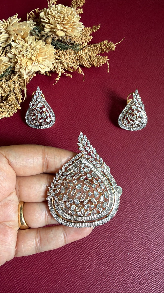 Anagha American Diamond teardrop pendant held in hand to show size, with matching earrings