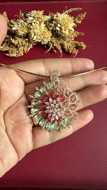 Josie rose gold-toned fusion pendant held in hand: pink and mint-green oval stones with white American Diamond swirl, on a slim hasli