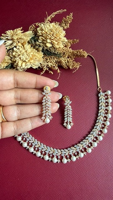 Irish leaf-drop pearl earrings held in hand with matching necklace