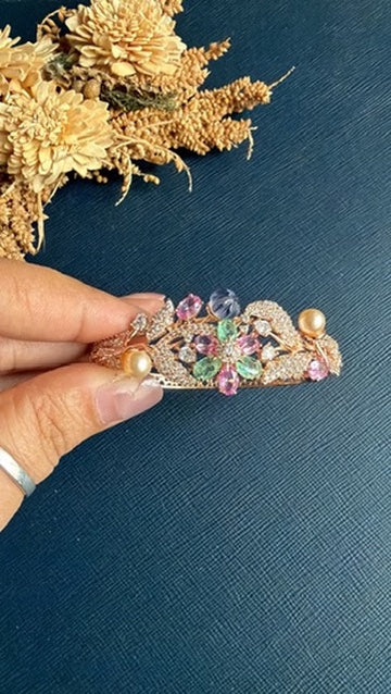 Chellan hinged rose gold bracelet held to show the flower spray from the side