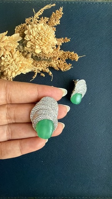 Sea green doublet stone stud held in hand to show its 1.25-inch size, with the second stud beside it