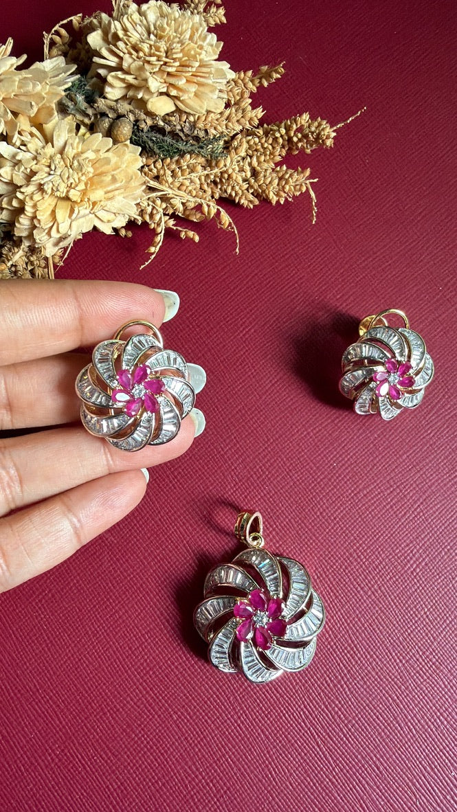 Mansi swirl earring held in hand to show its size, with the matching pendant below