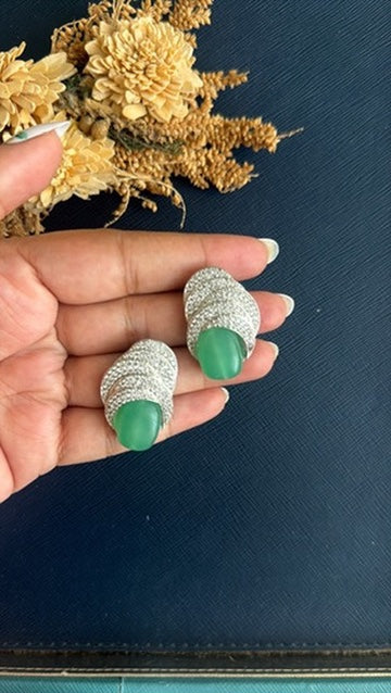 Pair of sea green doublet stone studs with white American Diamond wave bands, held in hand