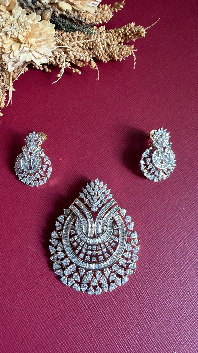 Needhi American Diamond pendant and matching earrings, front view: curved baguette bands framed by white pear-cut CZ stones on a gold-toned setting