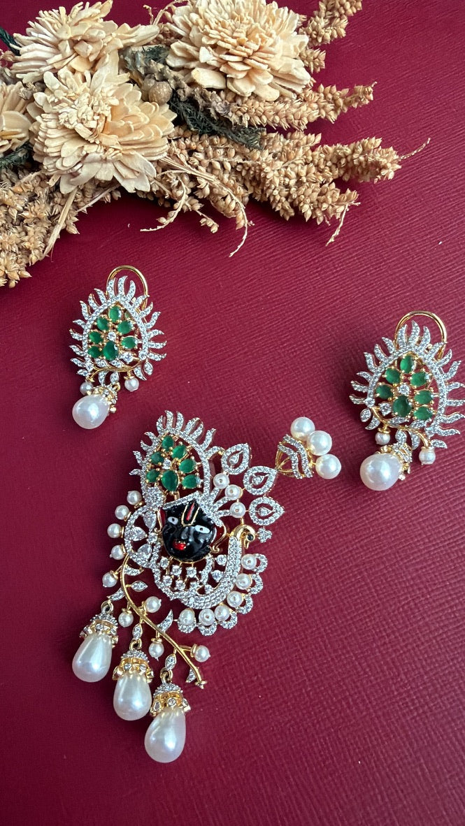 Krishika Shrinathji face pendant set with American Diamond, green stones and pearl-look drops