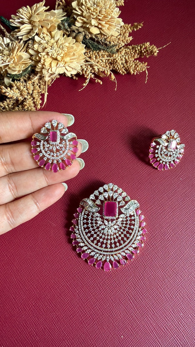 Rushika ruby-pink earring held in hand to show its size, with the matching pendant beside it