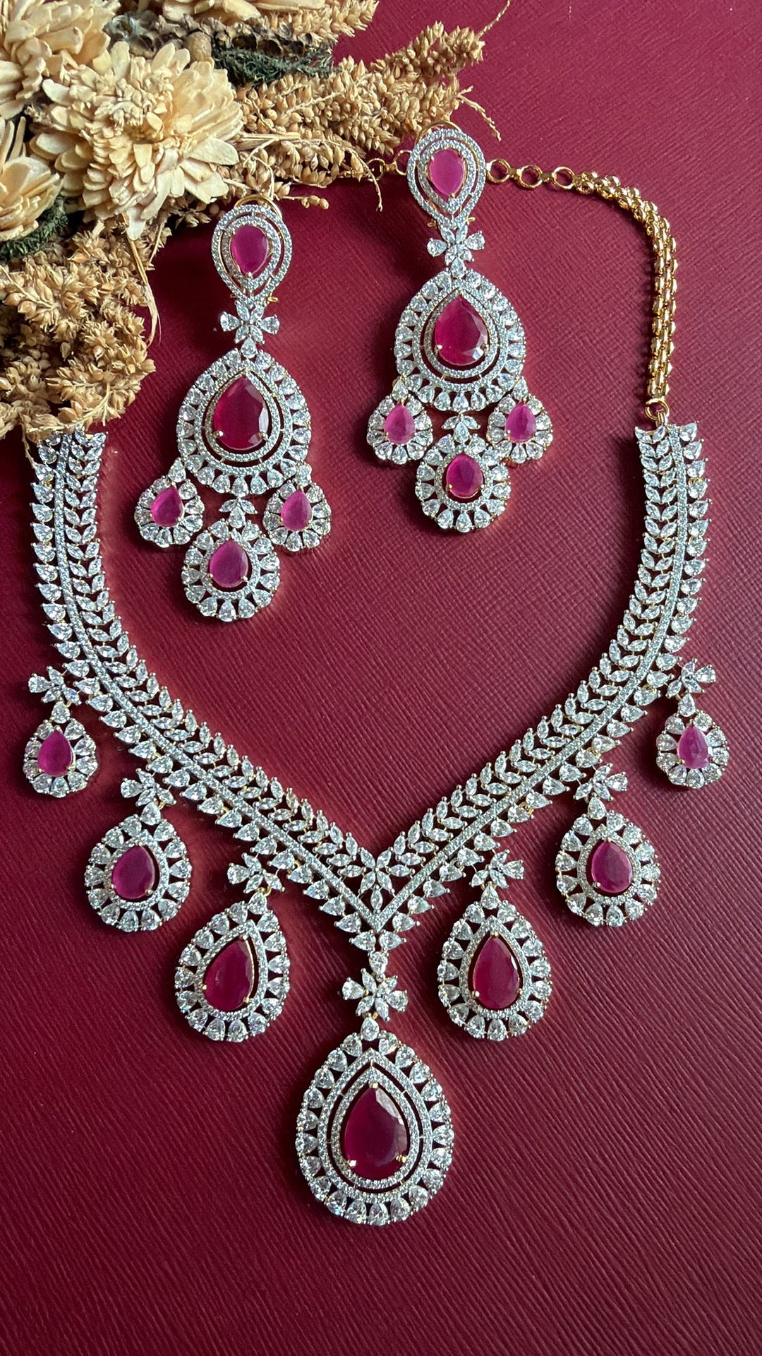Supriya ruby-pink and white American Diamond necklace and chandelier earrings flat lay