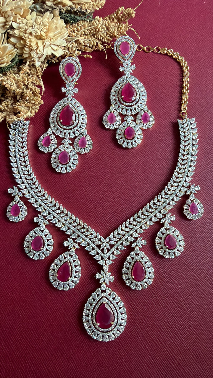 Supriya ruby-pink and white American Diamond necklace and chandelier earrings flat lay