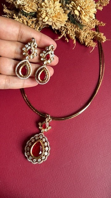 Clara Victorian hasli necklace with ruby-red teardrop pendant framed in white CZ, with matching earrings held in hand